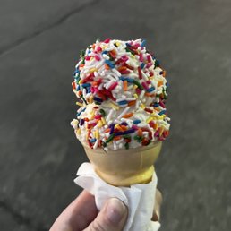 a hand holding an ice cream cone with sprinkles a hand holding an ice cream cone with sprinkles