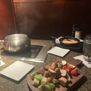 Photo of The Melting Pot - Jenks, OK, United States. About to make our loaded baked potato fondue, the cutting board had all of our "dippers". Apples, bread and vegetables.