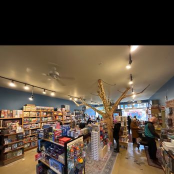 Cloud Cap Games - What a fun space! - A game store interior with shelves of board games, puzzles, and tabletop games, featuring a decorative tree with string lights. - Tabletop Games Near Me - Portland, Oregon
