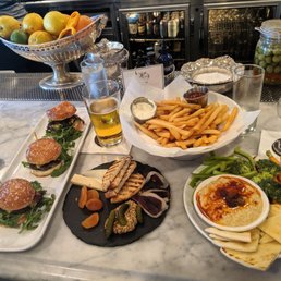 Happy Hour Bar Food. Sliders, fries, hummus, and board with a small selection not meat and cheeses.