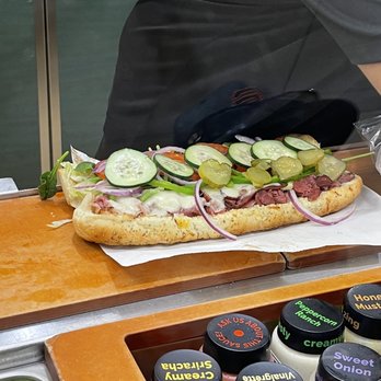 Subway - a person preparing a sandwich on a cutting board - Sandwiches Near Me - Baker, California Subway - a person preparing a sandwich on a cutting board - Sandwiches Near Me - Baker, California