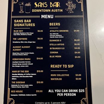 Sans Bar - Menu - The menu board for Sans Bar in Austin displays a list of signature mocktails, beers, and drink options with prices. It includes sections for signatures such as Blue Sky, The Ladybird, and Kobayashi Maru, along with beers like Athletic Brewing, Guinness, Stella Artois, and others. The board also lists ready-to-sip options and a special all-you-can-drink price. The design features a dark background with gold decorative borders and illustrations of drinks, emphasizing the bar's focus on non-alcoholic beverages and social drinking. - Bars Near Me - Austin, Texas