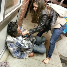 a woman helping a man on the sidewalk