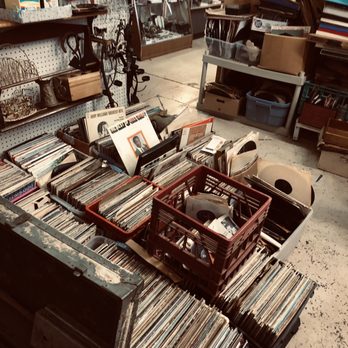 Fields Stable Antiques - Records - Vinyl records are organized in bins and baskets in a thrift store, with various vintage items and accessories visible in the background. - Antiques Near Me - Lockhart, Texas