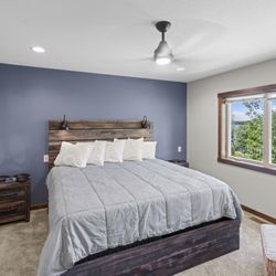 Big Sandy Lodge & Resort - Cabin 45: Spacious Main Floor King Suite, Featuring a Rustic Bed Frame, Natural Light, and Bedside Nightstand.