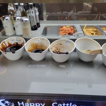 Happy Cattle - Part of the sauce bar with some fried appetizers (popcorn chicken, fries) in the back. - Korean Near Me - Chicago, Illinois