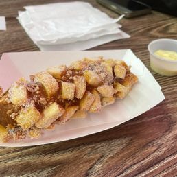 Potato dog filled with cheese and coated with sugar- cheese sauce on side. Potato dog filled with cheese and coated with sugar- cheese sauce on side.