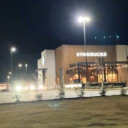 a starbucks on the corner of a parking lot at night