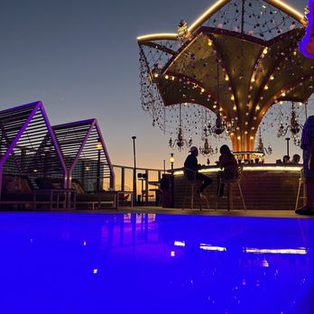 Golden Hour - people sitting at a bar with a carousel in the background - Cocktail Bars Near Me - Los Angeles, California
