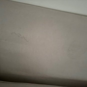 Mindful Moving Services - The image shows a close-up of a beige upholstered surface, likely part of a sofa or chair, with a small stain or mark on the fabric. The surface appears smooth with some minor imperfections. - Movers Near Me