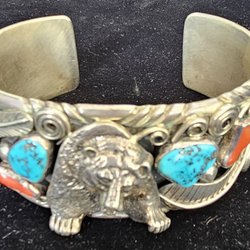 This is an American made all silver cuff bracele sculpted with a bear, red Buffalo turquoise, and traditional blue turquoise.