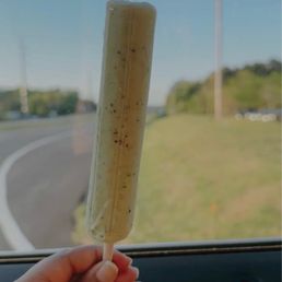 a person holding a banana on a stick