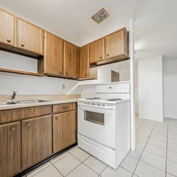Jordan Court Apartments - A kitchen with wooden cabinets and white appliances
