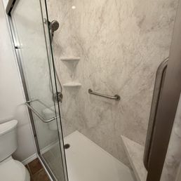 Floor to ceiling with 2 shelves, 2 grab bars, seat, and magnetic removable Moen shower head.  In pearl.