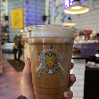 Dark Matter Coffee - a hand holding a cup of iced coffee - Coffee & Tea Near Me - Chicago, Illinois