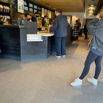 Starbucks - a woman standing in front of a counter - Coffee & Tea Near Me - Toronto, Ontario