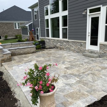 Grizscapes - Travertine raised outdoor living space with custom bench - Landscaping Near Me