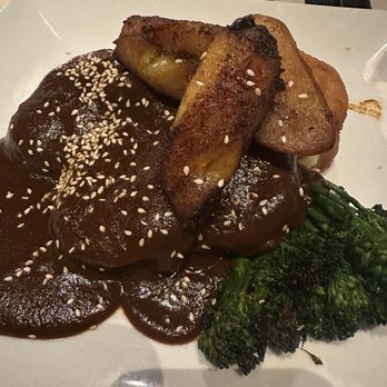 Cafe con Leche - Chicken Mole - A dish featuring chicken covered in mole sauce with roasted potato wedges and steamed broccoli on a white plate. - Mexican Near Me - Chicago, Illinois