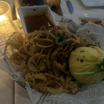Assaggio - Fried calamari served with a dipping sauce, garnished with herbs, on a table with plates, bread, and utensils. - Italian Near Me - Boston, Massachusetts