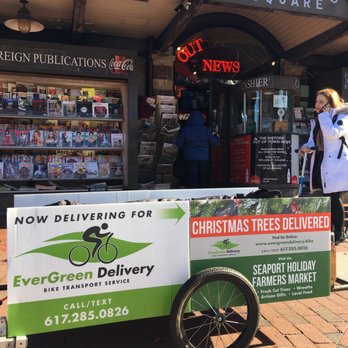 EverGreen Delivery - EverGreen Christmas Tree Delivery Trailer in Harvard Square, in front of historic Out of Town News - Christmas Trees Near Me - Boston, Massachusetts