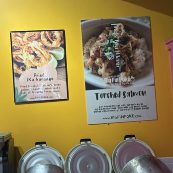 Big Fin Poké - Two posters on a yellow wall showcase menu items: fried calamari and torched salmon, with images and descriptions. - Poke Near Me - Melrose, Massachusetts