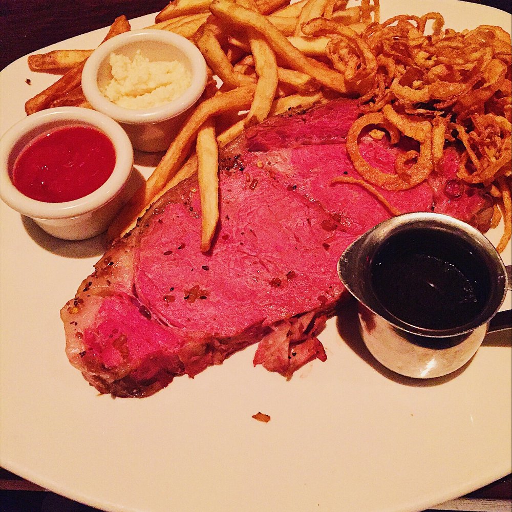 The Keg Steakhouse + Bar - Rib eye steak cooked rare served with au jus with a side of fries and fried onion strings - Steakhouses Near Me - Coquitlam, British Columbia The Keg Steakhouse + Bar - Rib eye steak cooked rare served with au jus with a side of fries and fried onion strings - Steakhouses Near Me - Coquitlam, British Columbia
