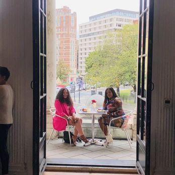 Patterson Mansion - Two women are seated at a table outside a historic building, with a cityscape and trees in the background, enjoying a meal. - Venues & Event Spaces Near Me - Washington, DC, District of Columbia