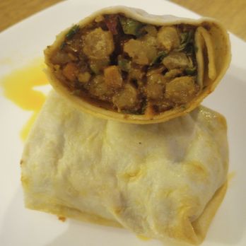 Cloudforest Coffee - Creamy Dill Chickpea Wrap. $8.50. - A creamy dill chickpea wrap with a soft tortilla exterior, cut open to reveal a filling of chickpeas, vegetables, and sauce, served on a white plate. - Coffee & Tea Near Me - Ottawa, Ontario