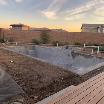 Bella Vista Pools - A backyard swimming pool is being built, with the pool structure visible and construction materials around it, during sunset. - Pool & Hot Tub Service Near Me