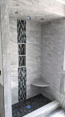 Complete Shower Upgrade - Natural Stone & Tile - Complete shower remodel with pebble mosaic floor and porcelain wall tiles. Area fully wrapped with waterproofing membrane for maximum protection. Clean, durable, and stylish result.