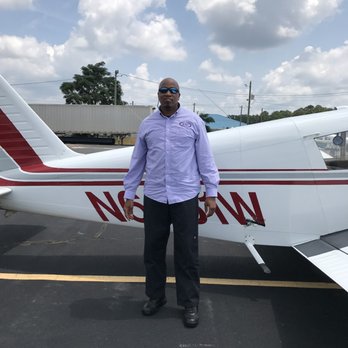 FlyBoys Flight Centers - A bald Black man wearing sunglasses, a light purple checkered button-down shirt with a circular logo on the left breast, and ... - Flight Instruction Near Me - Griffin, Georgia FlyBoys Flight Centers - A bald Black man wearing sunglasses, a light purple checkered button-down shirt with a circular logo on the left breast, and ... - Flight Instruction Near Me - Griffin, Georgia