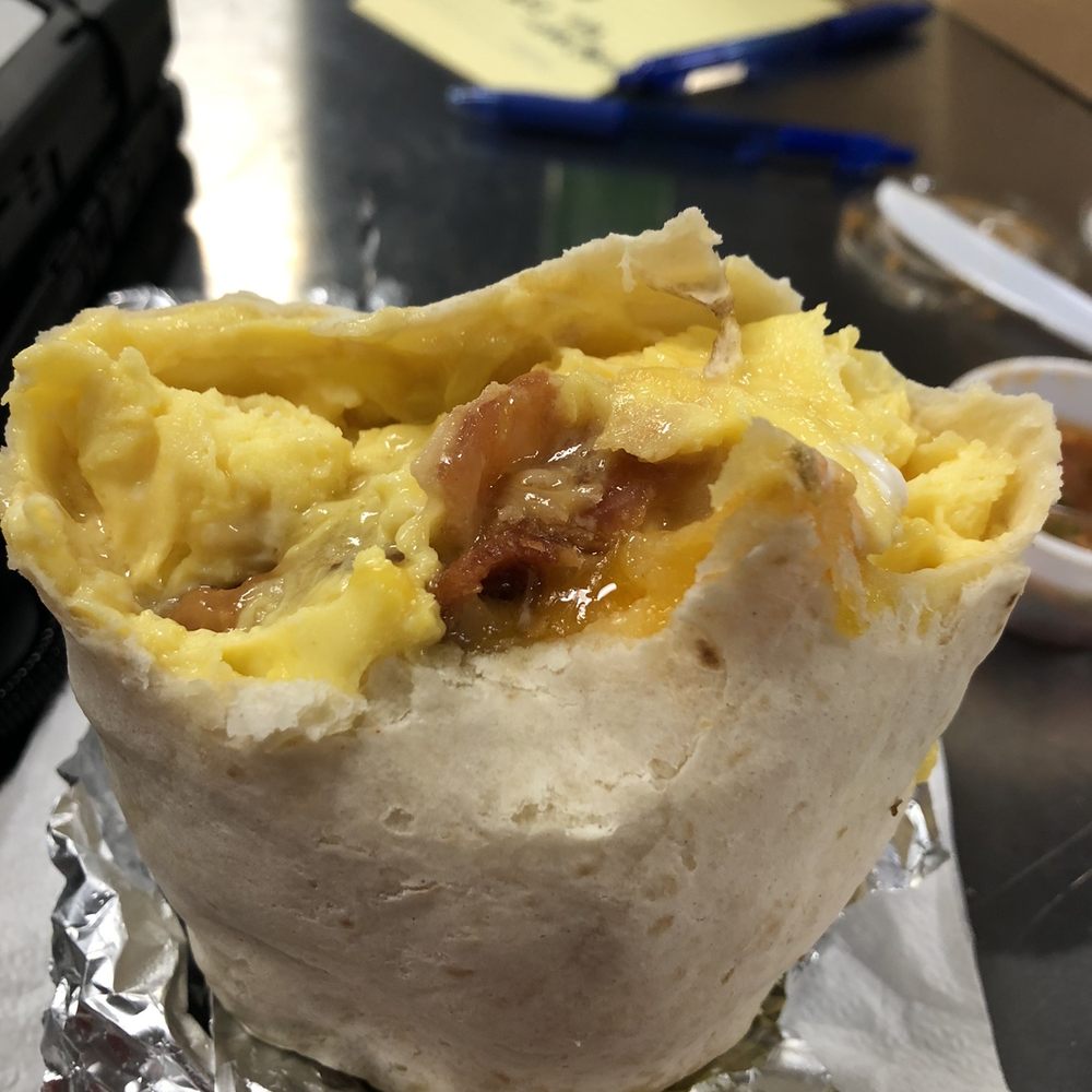 Half eaten, bacon and sausage burrito Half eaten, bacon and sausage burrito