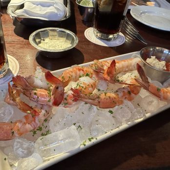 Pappadeaux Seafood Kitchen - Jumbo Shrimp Cocktail - A rectangular white dish contains jumbo shrimp on ice, garnished with herbs, accompanied by a small metal cup of cocktail sauce. - Seafood Near Me - Albuquerque, New Mexico