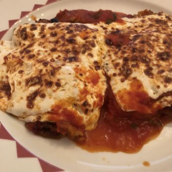 Berta's Chateau - a plate of lasagna - A dish featuring baked eggs topped with melted cheese and tomato sauce, served on a white plate with a side of meat, likely at an Italian restaurant. - Italian Near Me - Wanaque, New Jersey