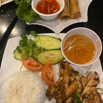 Pho Number One - Shrimp and Pork Spring Rolls - A plate with grilled meat, rice, sliced cucumbers, tomatoes, and cilantro, accompanied by dipping sauces and fresh vegetables. - Vietnamese Near Me - Mesa, Arizona