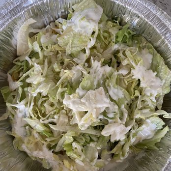 Chilo's - AVOCADO TOSTADA - The image shows shredded lettuce with a creamy dressing drizzled on top, served in a disposable aluminum foil container. The lettuce appears fresh and chopped into small pieces, with the dressing evenly distributed. The container is placed on a speckled surface, indicating it is ready for serving or takeout. - Bars Near Me - Brooklyn, New York