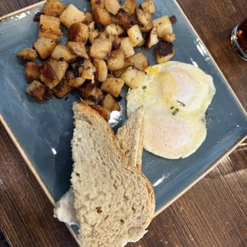 First Watch - The Fresh-Brewed Iced Tea - A breakfast meal featuring two fried eggs, toasted bread slices, and roasted diced potatoes served on a blue square plate. - Cafes Near Me - Tucson, Arizona