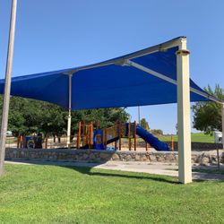 Travis White Park - Playground equipment under large sunshade.