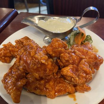 Cobblestones - Buffalo Tenders - A plate of buffalo tenders coated in sauce, served with a side of creamy dipping sauce and pickled vegetables. - Bars Near Me - Lowell, Massachusetts