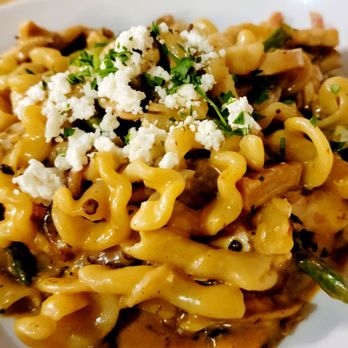 M'tucci's Italian - Chipotle Chicken Pasta Campanelle Pollo Alla Diavola - A close-up of a pasta dish featuring campanelle noodles mixed with pieces of chicken, topped with crumbled cheese and chopped herbs. The pasta appears coated in a sauce, and the dish is served in a white bowl, highlighting the textures and ingredients. - Italian Near Me - Albuquerque, New Mexico