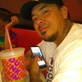 Dunkin' -  a man holding a drink and a cell phone - Donuts Near Me - Las Cruces, New Mexico