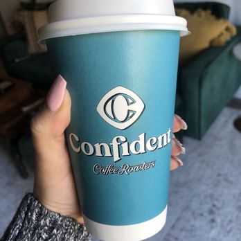 Confident Coffee Roasters - a hand holding a cup of coffee - Coffee & Tea Near Me - Fayetteville, Arkansas