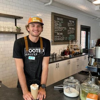 Rooted Coffee - a man standing behind a counter in a coffee shop - Coffee & Tea Near Me - Boise, Idaho