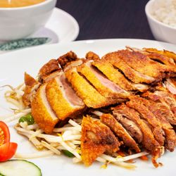 Knusprige Ente mit Erdnusssoße, serviert auf Sojasprossen, mit Reis