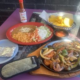 Veggie fajitas with rice, beans, and guacamole and corn tortillas.