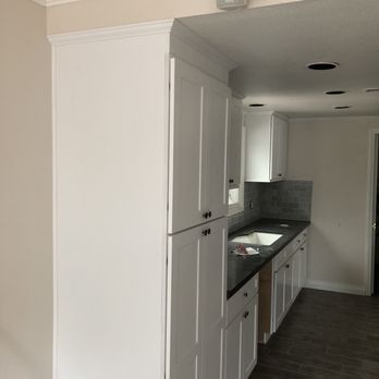 Action Restoration - a kitchen with white cabinets and black countertops - General Contractors Near Me - Ontario, California