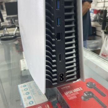 CompuTech - HDMI port was badly broken - The image shows a computer tower with a white side panel and a black front panel that contains various ports. From top to bottom, there are two USB 3.0 ports, an Ethernet port, an HDMI port, and a power input socket. The tower is placed on a glass surface, with a red box of wireless earbuds visible underneath. The background includes a retail environment with shelves and a person partially visible. - IT Services & Computer Repair Near Me - Garden Grove, California