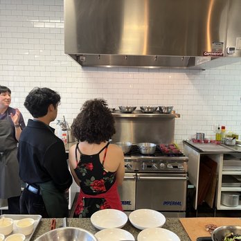 Cultivate Culinary Gatherings - Chef and assistant explaining the preparation of Filet Mignon (this part done for us) as 3 tables of 4 look on. - Cooking Schools Near Me - San Jose, California