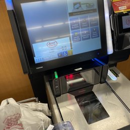 a cash register with a sushi in front of it - A Jewel-Osco self-checkout machine with a touchscreen interface and a sushi tray in front of it, located in a grocery store.