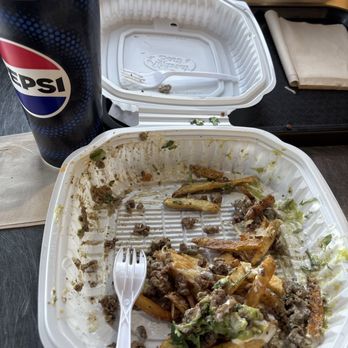 Cali Burrito Co - Cali style Asada Fries and Horchata drink - A mostly empty takeout food container with leftover fries and ground beef, a Pepsi cup, and utensils on a table at a restaurant. - Mexican Near Me - Albuquerque, New Mexico